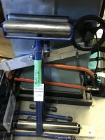 Full view showing blue metal roller stands and table roller behind with tags listing dimensions and lot number.