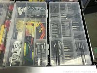 Top-down view of the open plastic organizer drawer containing multiple compartments with assorted drill bits, screws, wall anchors, and hardware accessories.
