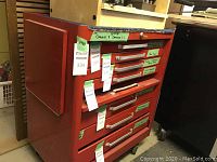 Front view of red metal seven-drawer tool cabinet showing drawer configuration and tags
