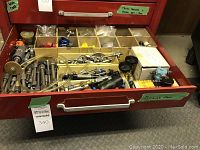 Red metal tool chest drawer opened showing multiple partitioned cardboard boxes filled with fittings and tools
