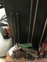 Four metal Speedcramp clamps placed on a wooden mount, three with blue screw handles and one with a red handle.
