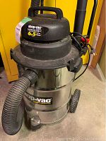 Full view of Shop-Vac unit on wheels with attached hose and power cord