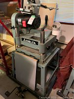 Front view of Delta planer mounted on metal rolling cart showing planer table and frame