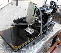 Left-front three-quarter view of black enamel Singer 221K with power cord and motor under bed