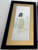 Framed elongated vertical painting of woman in yellow dress amid cattails, wood frame with golden matte