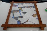 Photo of the framed art print showing the winter scene of snow-covered house rooftops with oak frame.