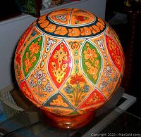Close-up view of the spherical parchment lamp shade showing colorful hand-painted floral patterns in orange, green, red and yellow.