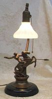 Front view of desk lamp featuring female warrior on rearing horse under lit milk glass shade