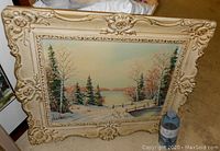 Framed winter landscape oil painting by artist A. Jalava showing full scene with frame and visible wooden bridge, pine trees, and autumnal trees.