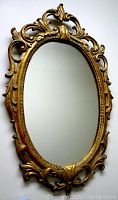 Front view of florentine style gilt wood oval mirror with detailed carving and gilded finish.