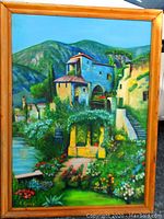 Front view of large landscape oil painting showing colorful buildings, garden, and hills, with visible artist signature B. Gyory and pine wood frame
