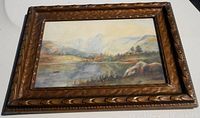 Full view of the framed watercolor landscape painting showing the carved textured wood Gothic style frame and the water scene inside.