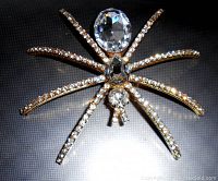 Close-up photo showing clear rhinestones on legs and three large clear rhinestones making up the spider's body on goldtone metal base.