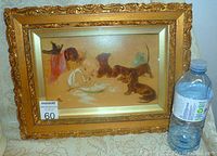 Full view of the framed oil painting showing the ornate gilt frame and the composition with the baby and dachshund puppies.
