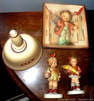 Top-down view showing all four items on a wooden surface: bell, plaque, and two figurines