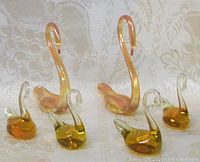 All six Murano glass swan figurines displayed on a light fabric background showing two large swans and four smaller swans grouped.