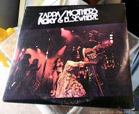 Front cover of 'Zappa/Mothers Roxy & Elsewhere' album showing band performing live on stage with red and purple lighting.