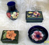 Top view of all four Moorcroft England pottery pieces showing the vase, bowl, and two boxes with floral painted designs.