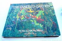 Front cover photo shows the large art book titled 'The Tangled Garden The Art of J.E.H. MacDonald, Text by Paul Duval' with a colorful garden scene artwork on the cover.