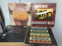 Four records laid flat: RCA-titled record with thong graphic, Doors LP, two Dave Clark Five LPs