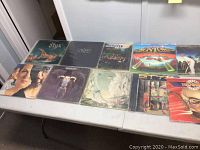Overview of nine vinyl record covers laid out on a table, including Styx, Eagles, Manassas, Boston and Prism