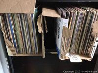 Photo of first box filled with vinyl records showing various album spines and wear on box edges.
