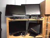 Wooden shelving holding four monitors: two on top shelf (HP 2210M front left, Samsung SyncMaster SA550 back right) and two on lower shelf (Samsung S20B300 left, black POS touchscreen right). Cables coiled on shelves.