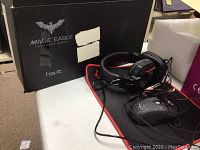 Photo showing the Havit Magic Eagle black box and headset on black mouse pad with red edge.