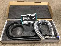Top view of the boxed faucet set with black U-shaped spout, braided hoses, and installation manual in foam packaging.