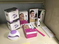 Photo showing blackhead remover vacuum devices with boxes and a pink tweezer accessory, and two nail polish dryers in white and purple.