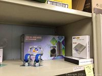 Photo showing two blue caster wheels and a boxed appliance holder set on shelf.