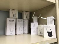 Shelf of assorted white and small WiFi repeater boxes showing multiple unopened units