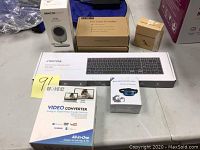 All five boxed items arranged on table: barking control collar, pet nail grinder, dragon touch camera model DT40, seenda wireless keyboard, and video converter.