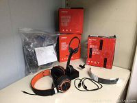 Four MPOW headsets with packaging and accessories on shelf, including boxed and loose headsets.