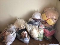 Photo showing seven sealed plastic bags of assorted bed linens, blankets, and sheets.