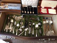 Drawer with assorted silverware including forks, spoons, knives, boxed teaspoons, and flatware with ivory handles
