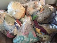 Full view of nine large clear plastic bags containing assorted bath linens and related textiles.