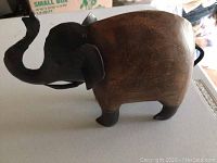 Side angle view of the elephant carving showing the wooden body and metal details