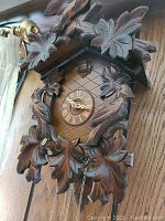 Close-up of the upper part of the cuckoo clock showing leaf carvings and a bird figure.