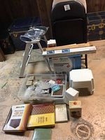 Overview photo of all items included: step ladder with padded seat, folding chairs, boxed clothing racks, clothes steamer box, small white plastic stool, clear storage bin with assorted items and photo albums