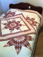 Front angle of queen bed with quilted patterned bedspread and wooden headboard