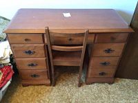Front view of the wooden desk with matching chair set between the desk pedestals.