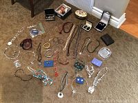 Overview of assorted costume jewelry spread on floor including necklaces, bracelets, earrings, and jewelry boxes.