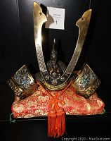Front view of samurai dragon kabuto helmet on red and gold brocade cushion