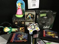 Full view of assorted gamers, toys, figurines and video games including Disney Infinity stands, Warcraft and Fallout-themed collectibles, Minecraft Craftables, Sega handheld Sonic the Hedgehog device and Sega Genesis cartridges.