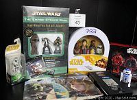 Photo shows a group of Star Wars collectible items including a boxed Empire Strikes Back read-along play pack with 3 figures, a PEZ 4 figure collectible gift set tin, a Dark Side Saga boxed gift set, a Return of the Jedi VHS tape, R2-D2 figure, and other collectibles.