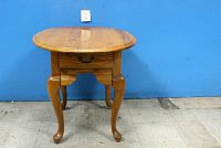 Front view of oak Queen Anne style side/end table with rounded rectangular top and cabriole legs.