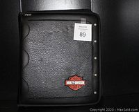 Front view of black textured Mead notebook with orange and black Harley-Davidson Motorcycles logo patch on cover