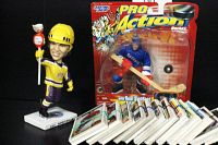 Photo showing Luc Robitaille bobblehead holding a mini Charms lollipop, sealed Wayne Gretzky Pro Action hockey figure in blue uniform, and many trading cards spread out in front.