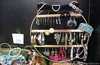 Earrings displayed on hanging rack showing different styles including hoops, black studs, and dangling earrings